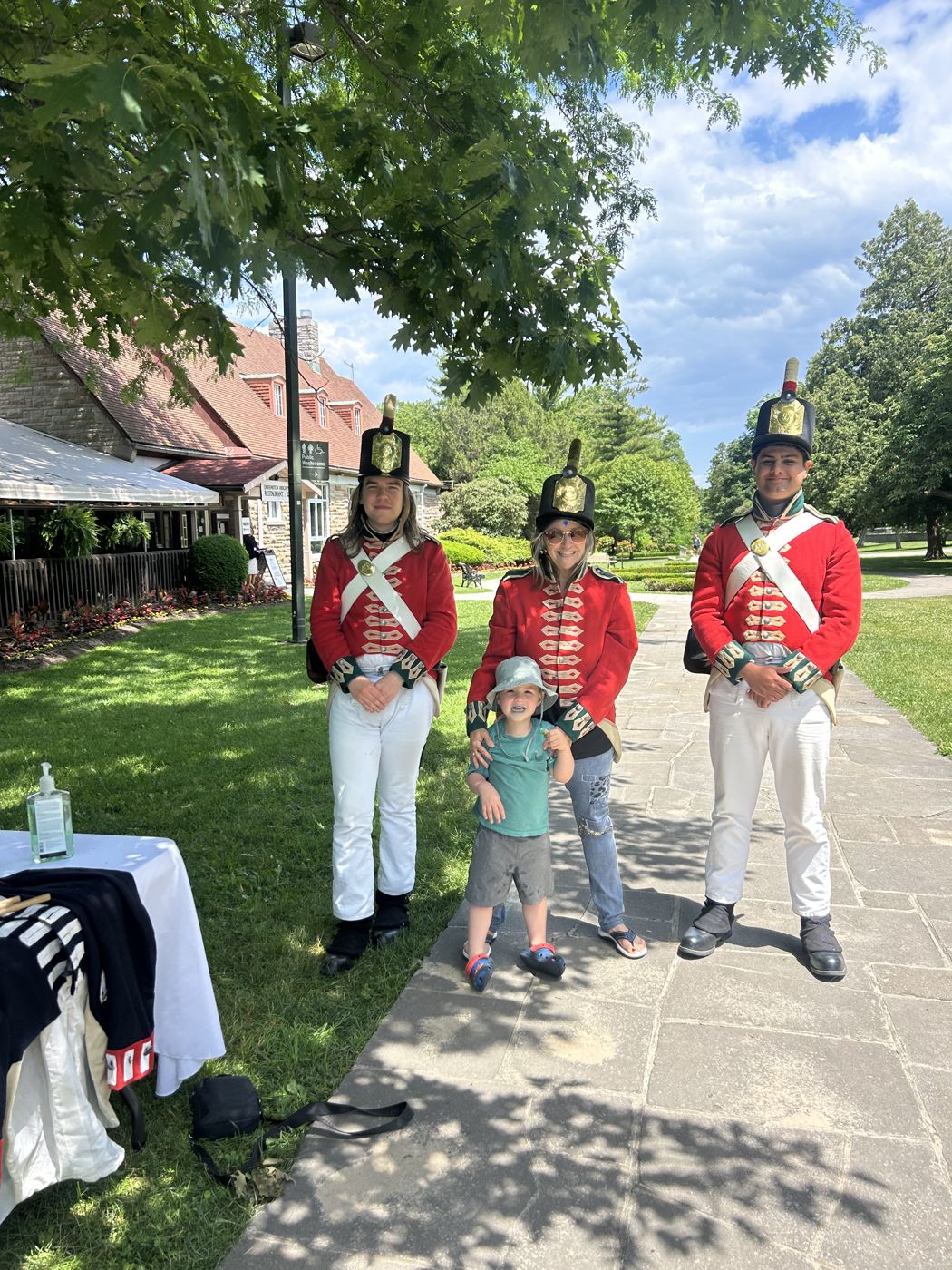 Un enfant pose entre des personnages en uniforme rouge d'époque, dans un parc de Niagara