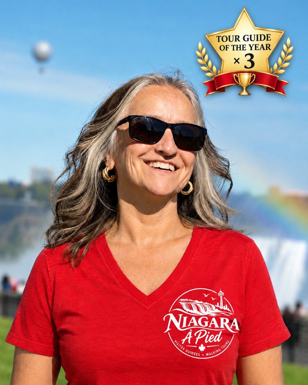 Martine Rioux, souriante en t-shirt rouge Niagara à Pied devant les chutes, avec l'insigne guide touristique de l'année trois fois